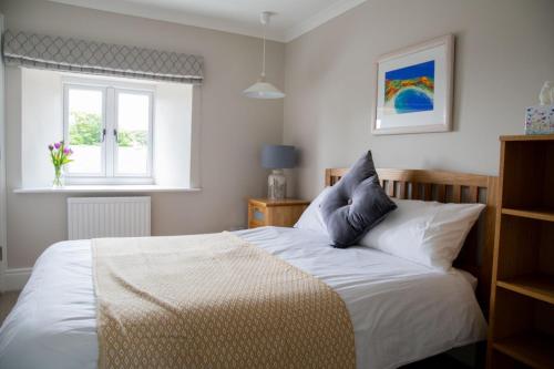 特鲁罗Tresithick Vean Bed and Breakfast的一间卧室配有一张带白色床单的床和一扇窗户。