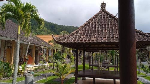 金塔马尼Hotel Segara的棕榈树庭院中一个带屋顶的凉亭