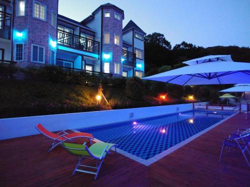 统营市贝尔加里旅馆的一座房子,设有游泳池、两把椅子和一把遮阳伞