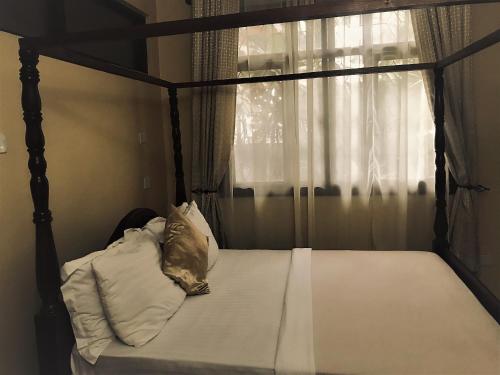 达累斯萨拉姆Transit Airport B&B的一间卧室配有一张天蓬床和窗户