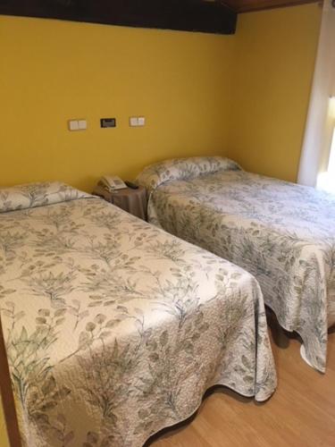OricáinHostal Rural Oricáin的黄色墙壁客房的两张床