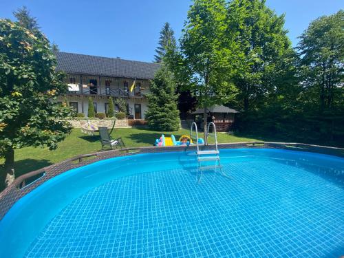 米库利钦Zorianyy Guest House的一座带房子的庭院内的游泳池