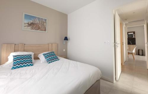 里夫杜海滩Résidence Prestige Odalys Rêve d'île的一间卧室配有白色的床和2个蓝色枕头