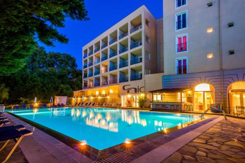 科孚镇Corfu Hellinis Hotel的夜间在酒店前的游泳池