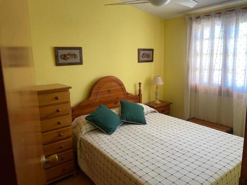 贝尼卡西姆Adosado con piscina y tenis的一间卧室配有一张带两个绿色枕头的床