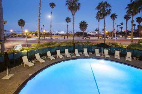 圣巴巴拉西海滩海滨宾馆的游泳池在晚上设有椅子和棕榈树