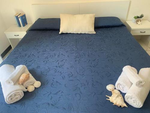 卡托利卡HOTEL LA PERGOLA的一张带毛巾的蓝色床和里面装满动物的