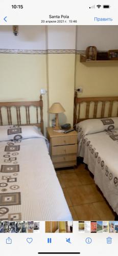 圣波拉Прекрасная Квартира в центре города Санта Пола的一间卧室配有两张床和一个带灯的床头柜