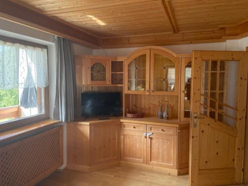 圣维吉利奥Ciasa Fam Comploi的客厅配有木制橱柜和平面电视。