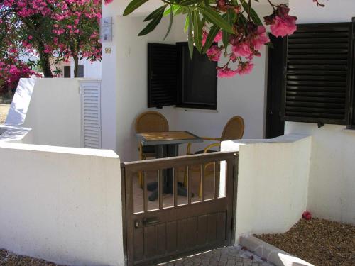 马林堡Retur Algarve Beach House的一座房子,设有大门和一张粉红色花的桌子