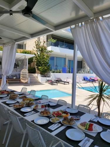 罗希姆诺Made of Blue luxury suites collection的游泳池旁的餐桌上放着食物