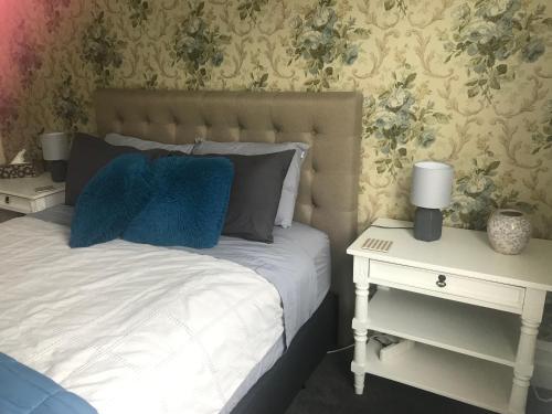 CartertonAratahi Cottages - West Wing的一间卧室配有一张带蓝色枕头的床和一张边桌