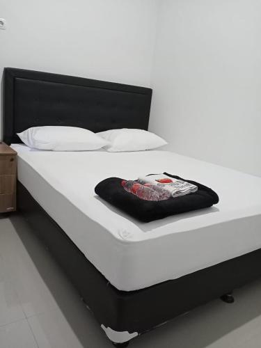 班图尔Srikandi Baru Inn Blok O的一张带黑色床头板和白色枕头的白色床