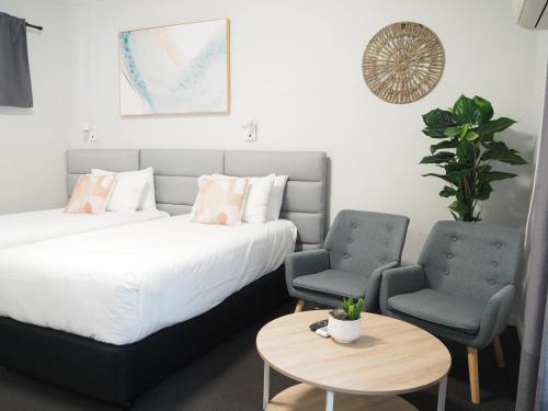 华纳海湾海滨大道汽车旅馆的一间卧室配有一张床、两把椅子和一张桌子