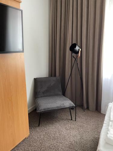杜塞尔多夫MAX Hotel Düsseldorf Self-Check-in的一间带椅子、一盏灯和电视的房间