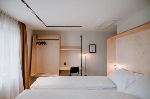 阿尔邦Hotel Müllers Self-Check-In的卧室配有白色的床和书桌