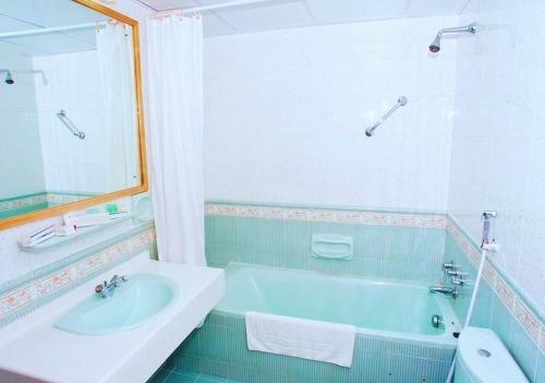 马斯喀特萨费酒店套房的浴室配有蓝色浴缸和水槽