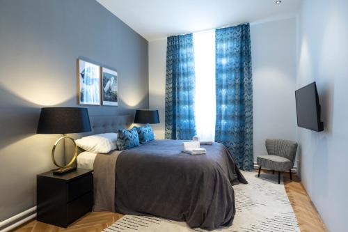 雷茨sgrafit apartments的一间卧室配有一张带蓝色窗帘的床和电视。