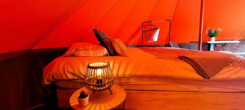 龙塞Fiertelmeers Boutique Glamping的红色的房间,配有一张床和一张带台灯的桌子