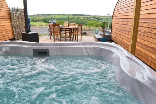 LanchesterDerecroft Glamping Luxury Lodgepods的后院的热水浴池,配有桌椅