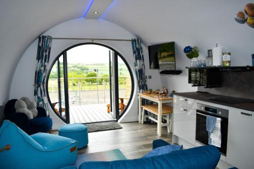 LanchesterDerecroft Glamping Luxury Lodgepods的一间带拱形门廊的客厅和一间带蓝色椅子的厨房