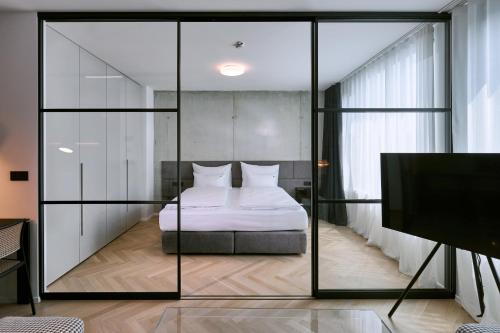 卢布尔雅那NEU RESIDENCES smart stay的带玻璃墙的卧室,配有一张床和电视