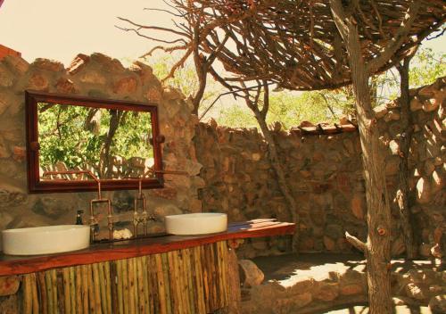 KhowaribKhowarib Lodge的石头浴室设有两个水槽和一棵树