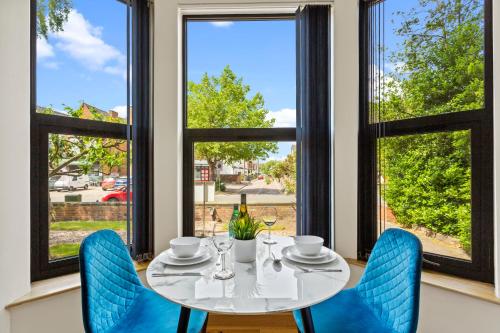 诺丁汉West One Studios的一间配备有桌子和蓝色椅子及窗户的用餐室