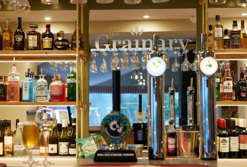 斯卡伯勒The Grainary Boutique Hotel的酒吧提供许多瓶装酒精饮料和时钟