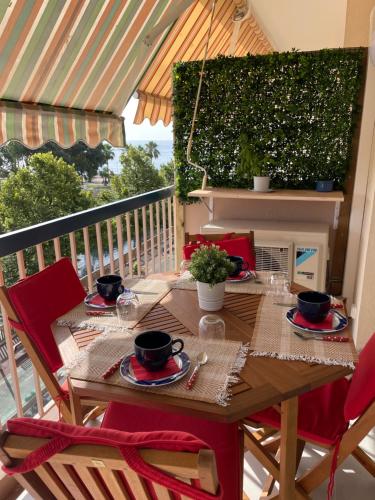滨海卡涅Appartement rénové, terrasse vue mer的阳台上配有一张带红色椅子的木桌