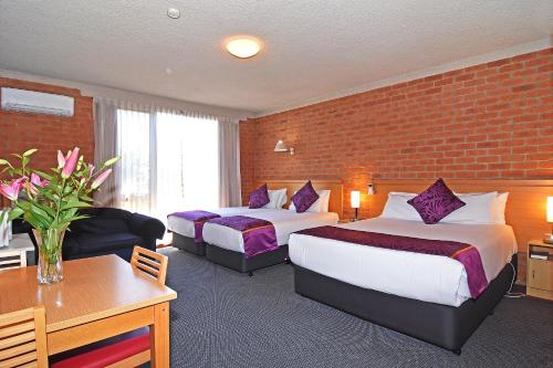 巴拉腊特Main Lead Ballarat Motel的酒店客房带两张床和砖墙