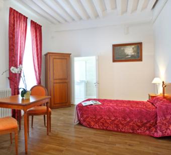 欧坦Villa Médicis AUTUN的一间卧室配有红色的床和桌椅