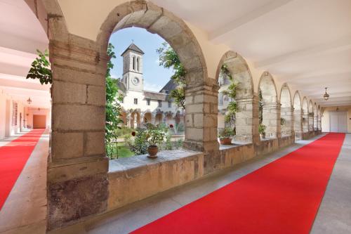 欧坦Villa Médicis AUTUN的一条铺有红地毯的空走廊和一个教堂
