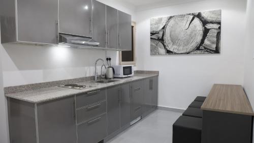 科威特BHomed Furnished Apartments的厨房配有灰色橱柜和台面
