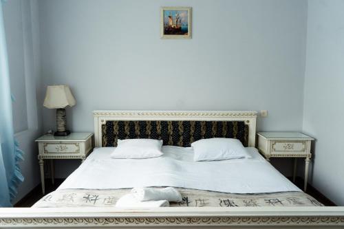 第比利斯Hotel White House的一张带两个床头柜和两张桌子的白色床