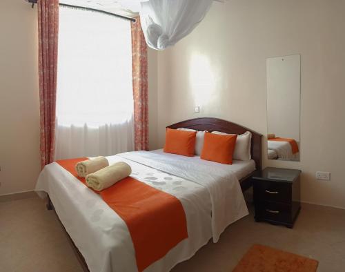 基苏木MILIMANI DRIVE LIVINGs的一间卧室配有带橙色枕头的床和窗户。