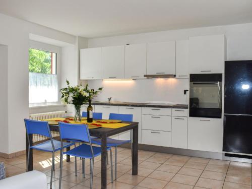 MagadinoApartment Le Bolle by Interhome的厨房配有白色橱柜和一张带蓝色椅子的桌子。