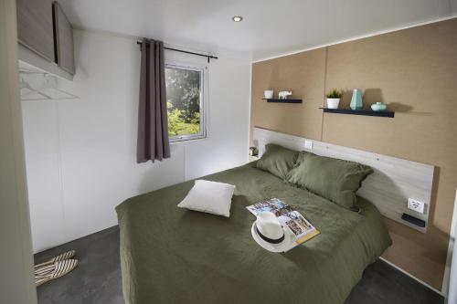 La DouzeLe Domaine du Bois Coquet的一间卧室配有一张绿床,上面有帽子