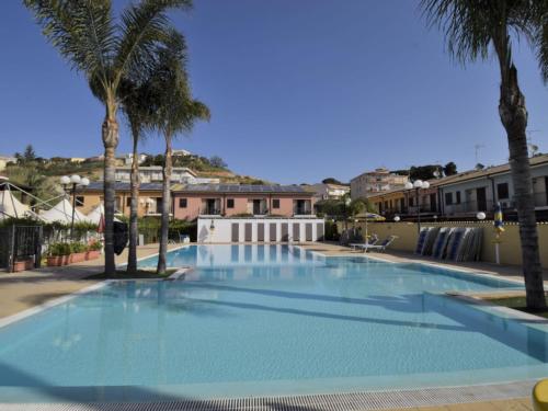 恩佩多克莱港Apartment L'Ancora-2 by Interhome的一座种植了棕榈树和建筑的大型蓝色游泳池