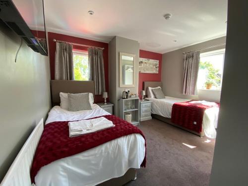 阿什比德拉祖什The Beeches, Ashby-de-la-Zouch的红色墙壁客房的两张床