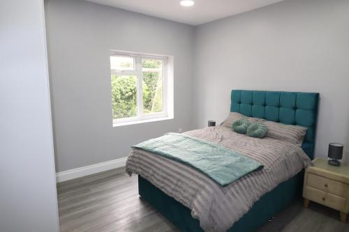 达特福德1 Bed Flat, Fibre Broadband, New, Washer Dryer, 10 mins from city centre的一间卧室配有一张带蓝色床头板的床和窗户