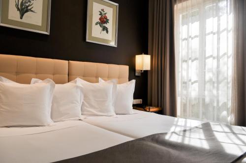 塞维利亚圣吉尔酒店的卧室配有一张带白色枕头的大床和窗户。