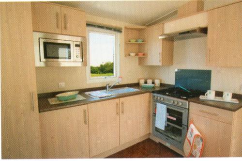 帕兹托Golden Burn Cottage Caravan的厨房配有水槽、炉灶和微波炉