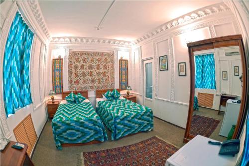 布哈拉明兹法酒店的一间带两张沙发的卧室和一间带蓝色窗帘的房间