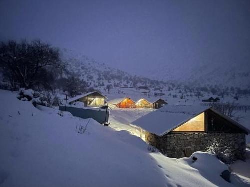 吉诺卡斯特Camping Cajupi的雪覆盖着的房屋,里面装着灯