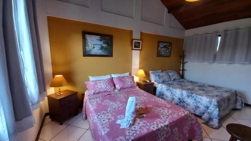 布希奥斯Flats Tartaruga Búzios的一间卧室配有两张带粉红色床单的床