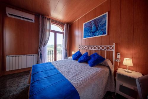 格拉塔略普斯Cassola Del Priorat的一间卧室配有一张带蓝色枕头的床和一扇窗户。