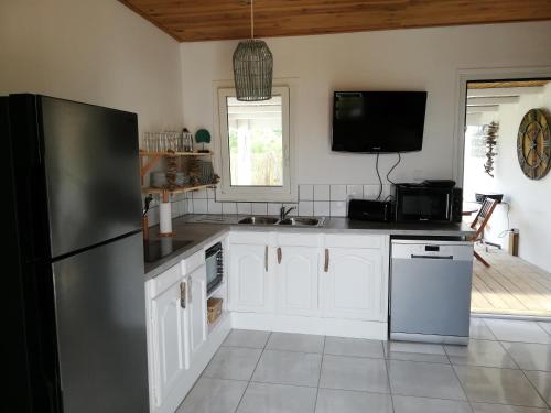 厄唐萨雷Cottage Tropical的厨房配有白色橱柜和黑色冰箱。