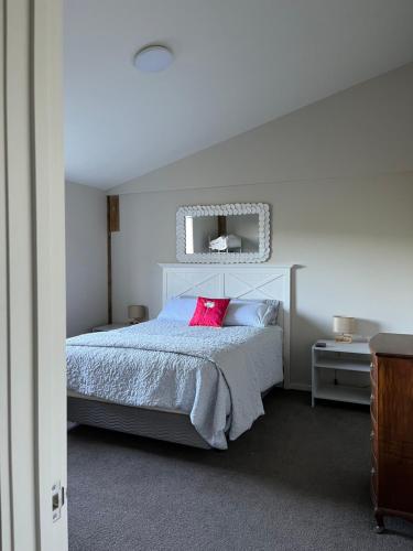 马塔卡纳Kahu Farm Apartment的一间卧室配有一张带粉红色枕头的大床