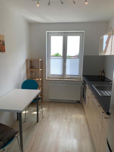 爱尔福特Apartment Am Jakobsweg的厨房配有桌子、水槽和2扇窗户。
